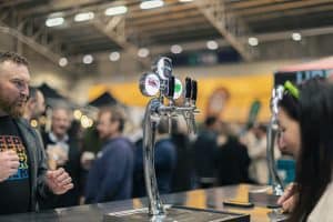 Cold craft beer at Taranaki Beer Festival with lively crowd and beer taps in action.