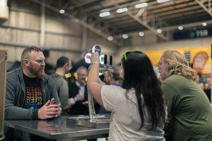 Premium craft beer tasting at Taranaki Beer Festival in an indoor venue with patrons enjoying local brews.