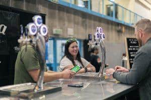 Bright cheerful woman serving craft beer at Taranaki Beer Festival in New Zealand.
