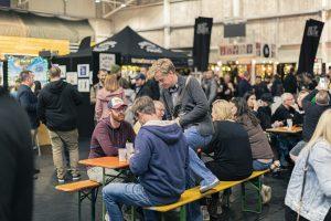 Vibrant crowd enjoying Taranaki Beer Festival with craft beers and lively atmosphere in indoor venue.