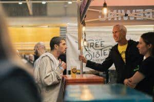 Festive scene at Taranaki Beer Festival with people tasting craft beers under warm lighting.