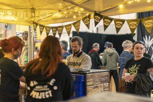 Vibrant scene at the Taranaki Beer Festival with beer enthusiasts enjoying craft beers under a festive yellow tent.