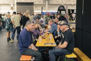 Vibrant scene at Taranaki Beer Festival with people enjoying craft beers and socialising in indoor event space.