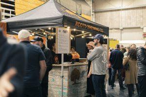 Taranaki Beer Festival, Roots Brewing Co expo tent, lively crowd enjoying craft beers, indoor beer festival, local breweries NZ.