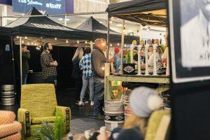 Vibrant scene at the Taranaki Beer Festival showcasing craft beer stalls, live attendees, and cozy outdoor seating.