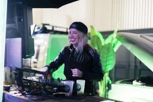 Vibrant woman DJ playing music at Taranaki Beer Festival, outdoor event, lively atmosphere, entertainment, craft beer, and DJ performance.