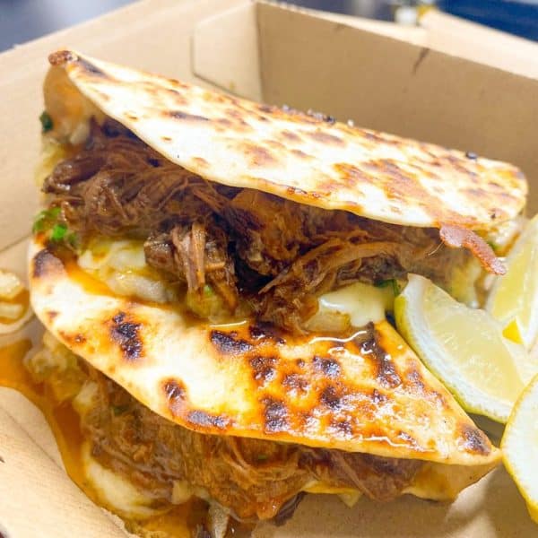 Savory pulled beef burger with cheese, lemon wedges, and toasted bun at Taranaki Beer Festival.
