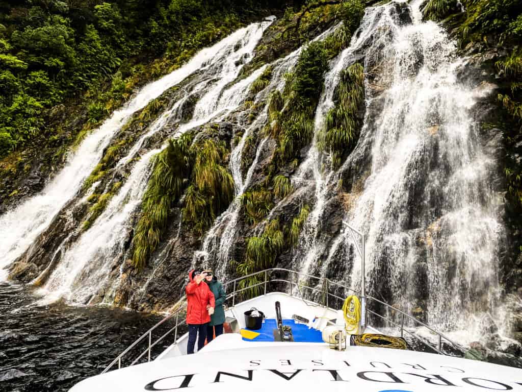 Southern Secret overnight cruise boat under waterfall in Doubtful Sound, Fiordland