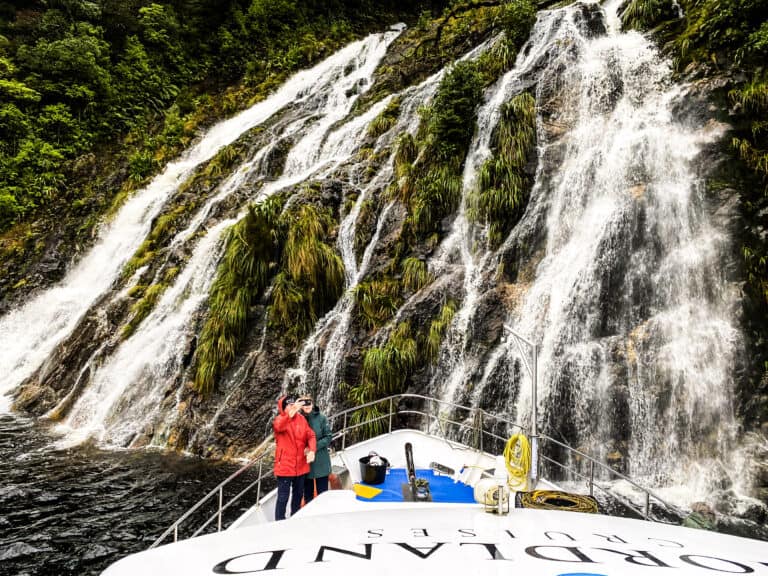 Southern Secret overnight cruise boat under waterfall in Doubtful Sound, Fiordland