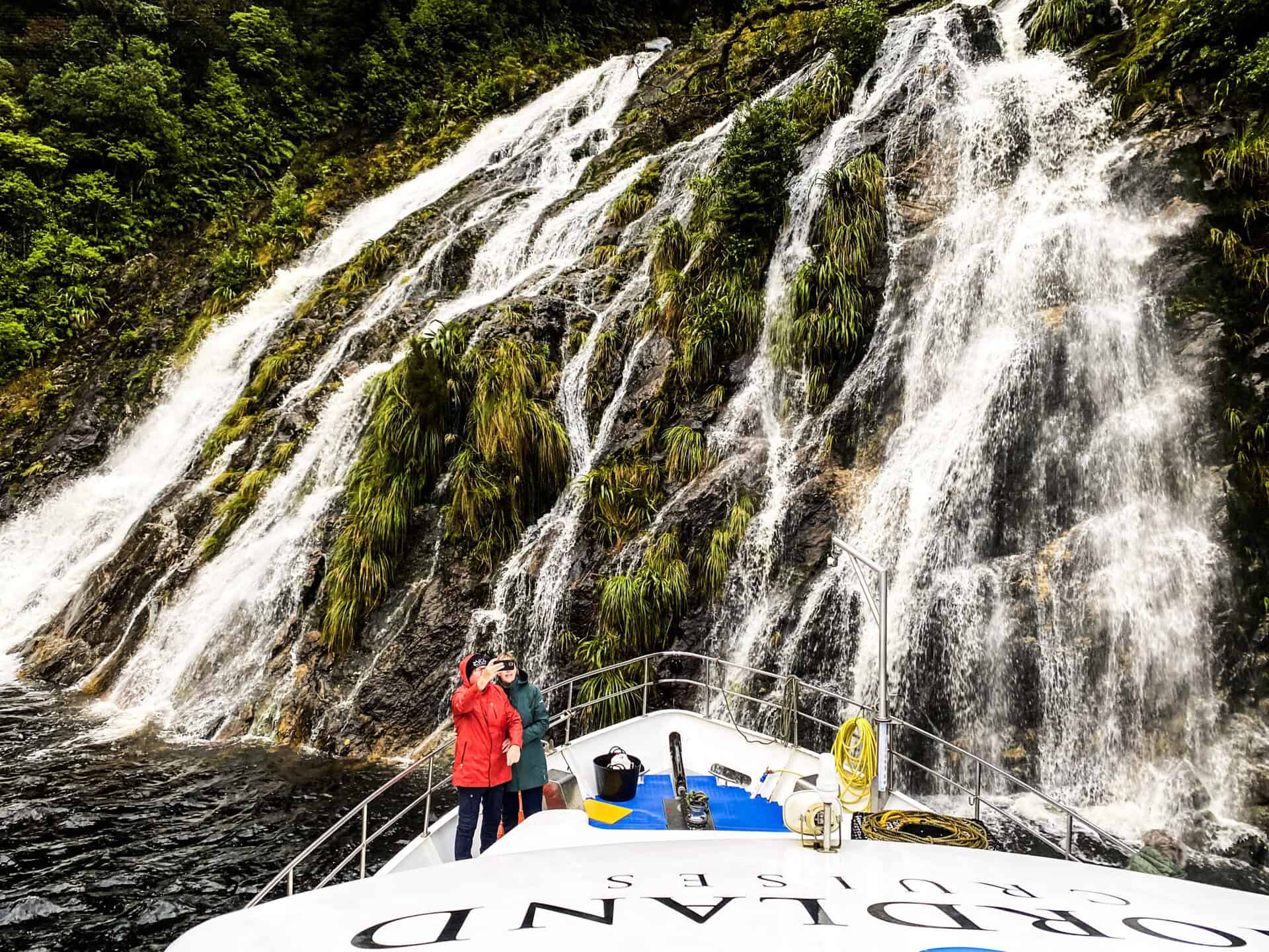Southern Secret overnight cruise boat under waterfall in Doubtful Sound, Fiordland