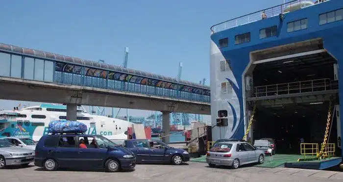 Puente peatonal y ferry en Tetuán, con coches y barcos en el puerto.