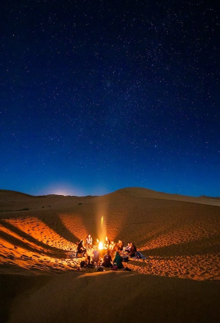 Personas disfrutando de una fogata bajo las estrellas en el desierto de Tetuán, Marruecos.
