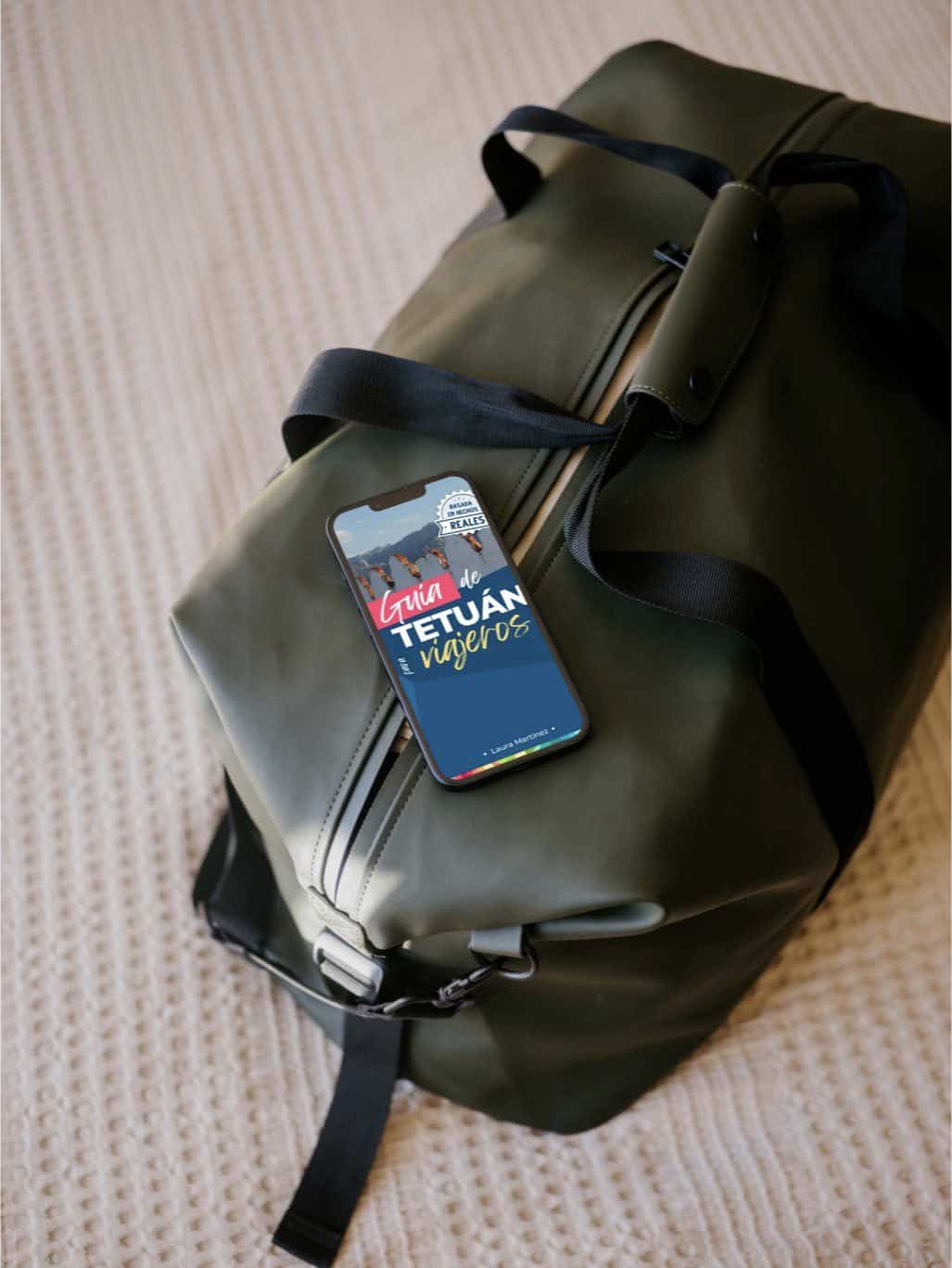 Mochila de viaje con guía digital de Tetuán en un teléfono móvil, lista para explorar la ciudad.