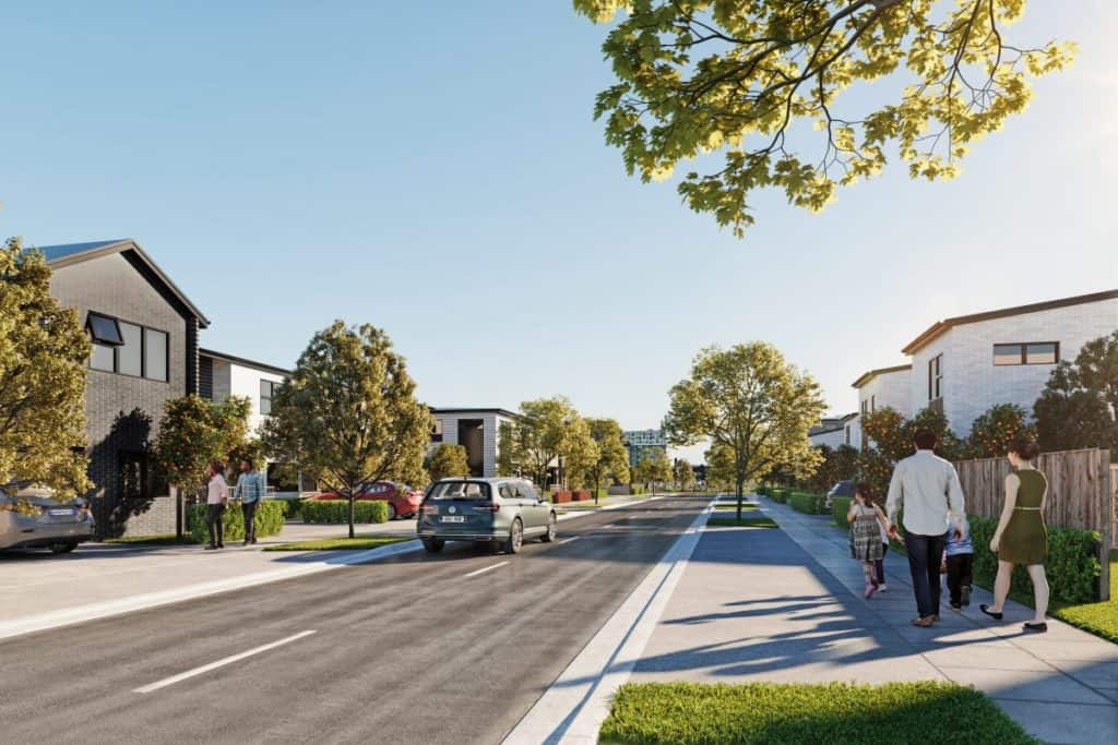 Modern residential neighbourhood street with new homes and families walking, showcasing Te Tumu Kāinga community living in Auckland.