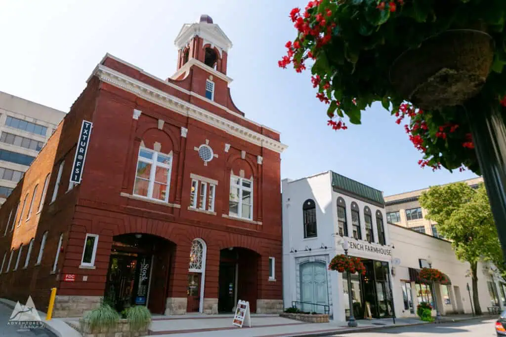 Exterior of the Fire Station One building on a street in downtown Roanoke. The building is red brick with symmetrical windows and large arches on the lower floor. There is a bell tower on the top resembling Independence Hall.