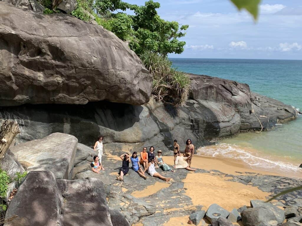 Bãi Đầm Trầu, Côn Đảo. Bãi đá nhô ra biển. Nhóm phụ nữ ngồi trên bãi cát.