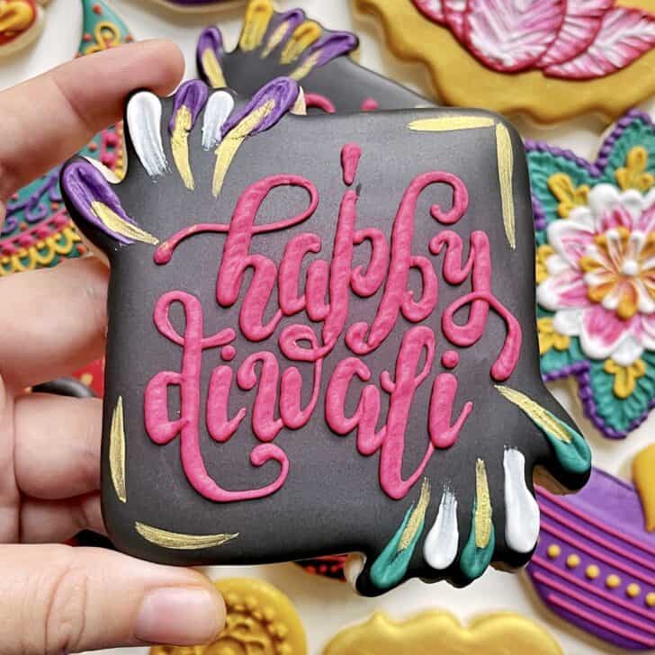 photo of writing with royal icing on a cookie: pressure piped saying HAPPY DIWALI