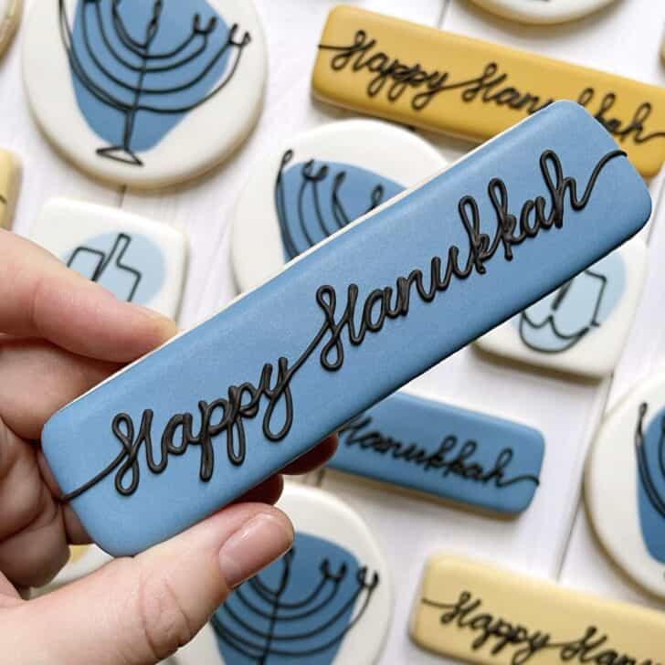 photo of writing with royal icing on a cookie: script saying HAPPY HANUKKAH
