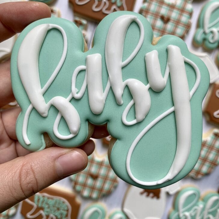 photo of writing with royal icing on a cookie: pressure piped saying BABY