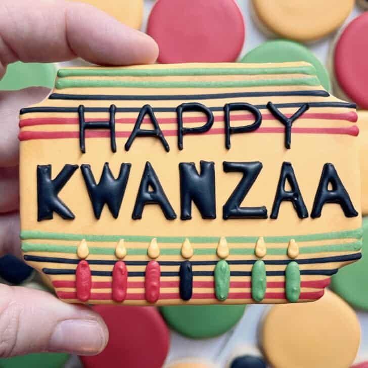 photo of writing with royal icing on a cookie: pressure piped saying HAPPY KWANZAA