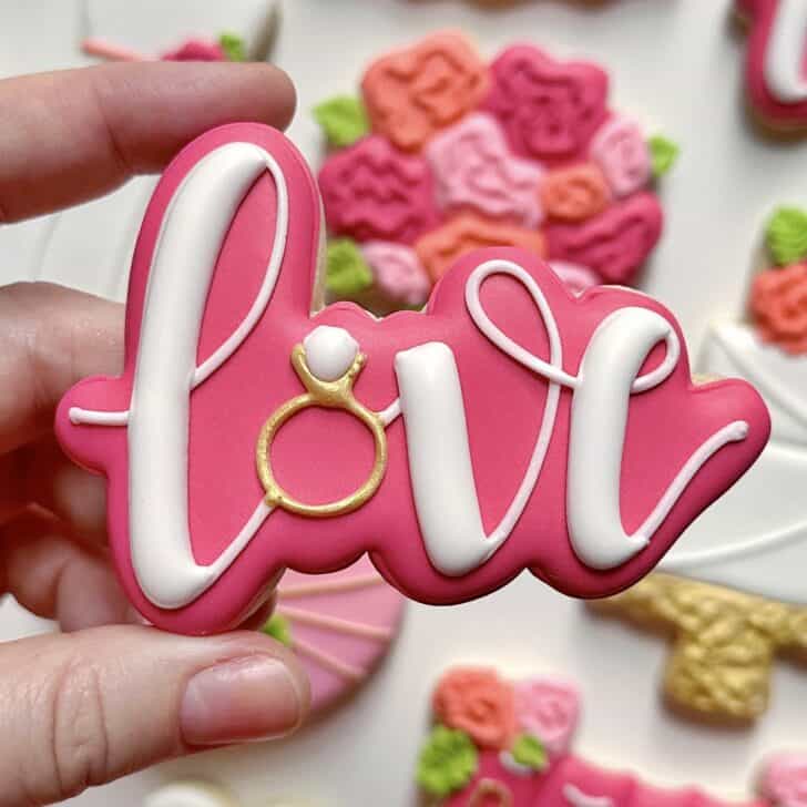 photo of writing with royal icing on a cookie: pressure piped saying LOVE