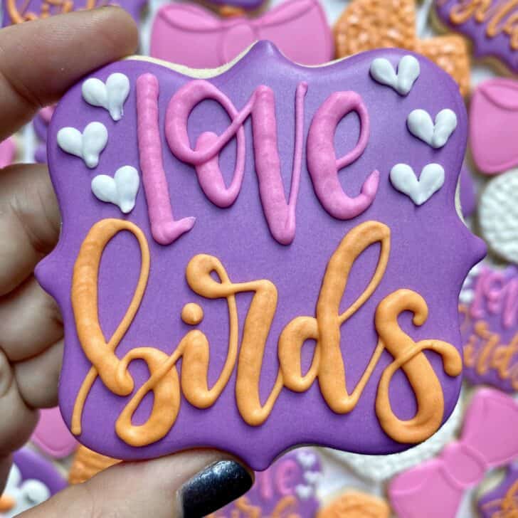photo of writing with royal icing on a cookie: pressure piped saying LOVE BIRDS