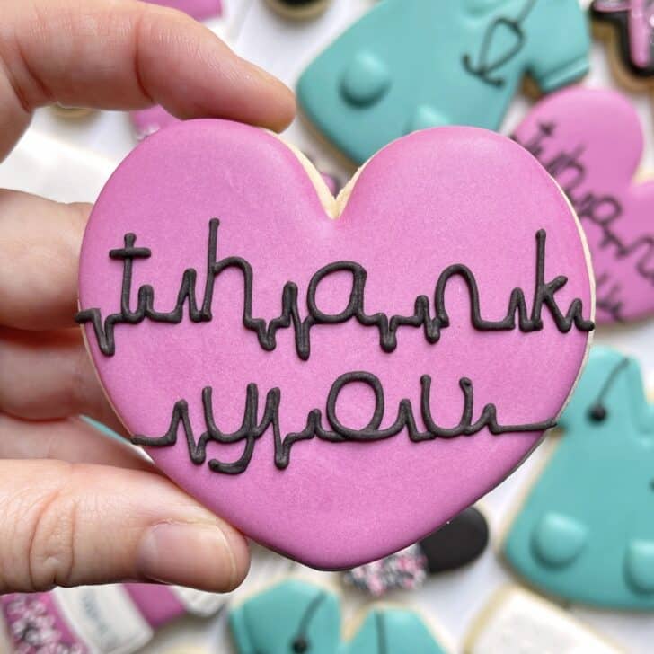 photo of writing with royal icing on a cookie: script saying THANK YOU