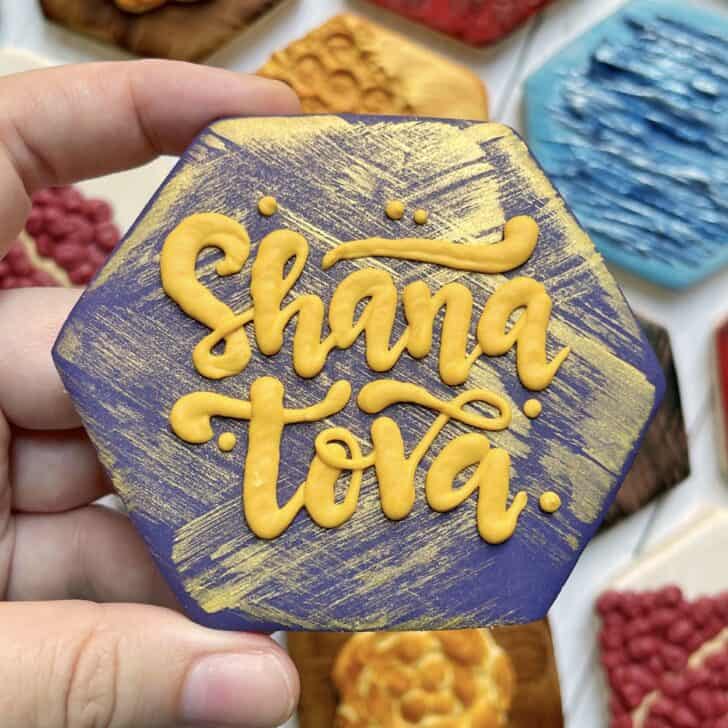 photo of writing with royal icing on a cookie: pressure piped saying SHANA TOVA