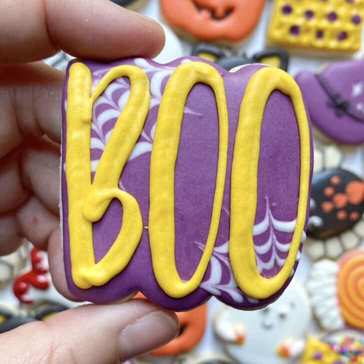 photo of writing with royal icing on a cookie: pressure piped saying BOO