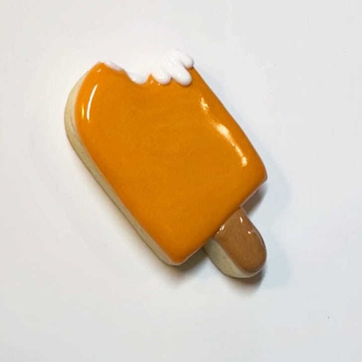 Step-by-step instructions for how to decorate orange creamsicle cookies with royal icing