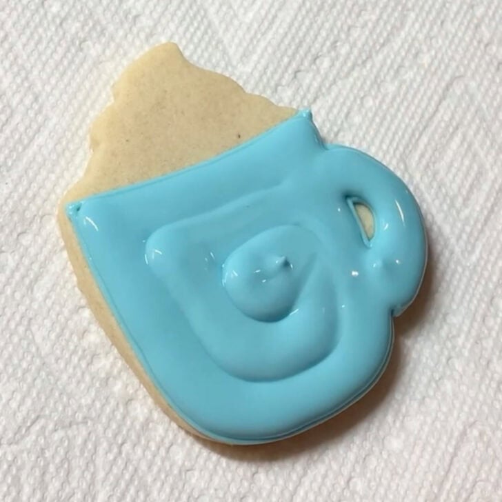 Step-by-step decorating instructions for how to decorate snowflake mug cookies with royal icing