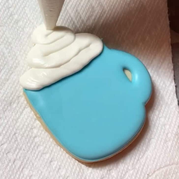 Step-by-step decorating instructions for how to decorate snowflake mug cookies with royal icing