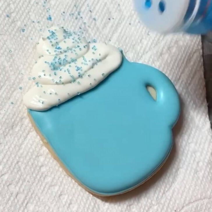 Step-by-step decorating instructions for how to decorate snowflake mug cookies with royal icing