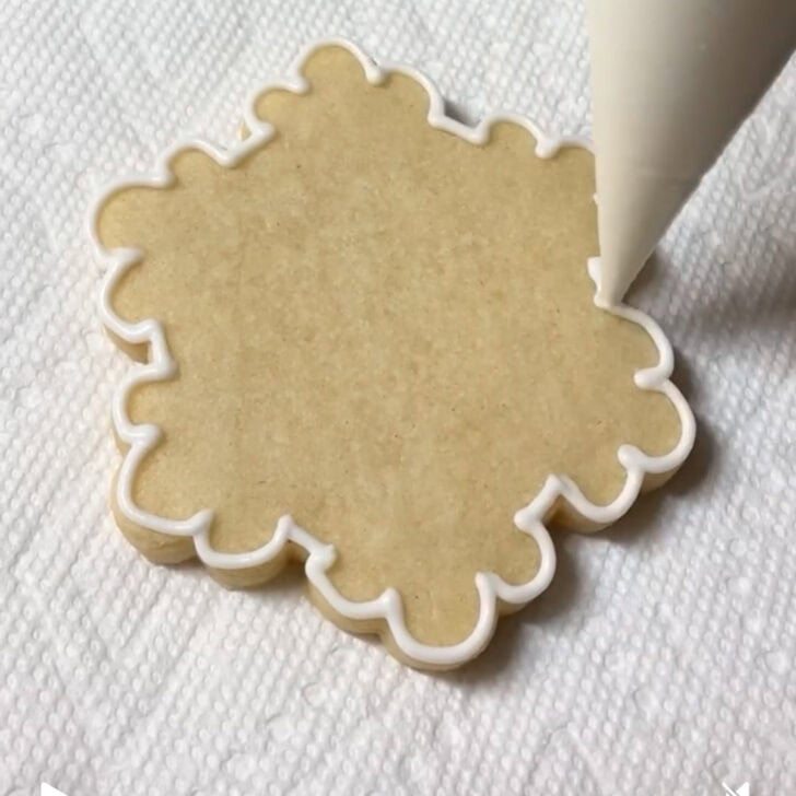 Step-by-step decorating instructions for how to decorate snowflake cookies with royal icing