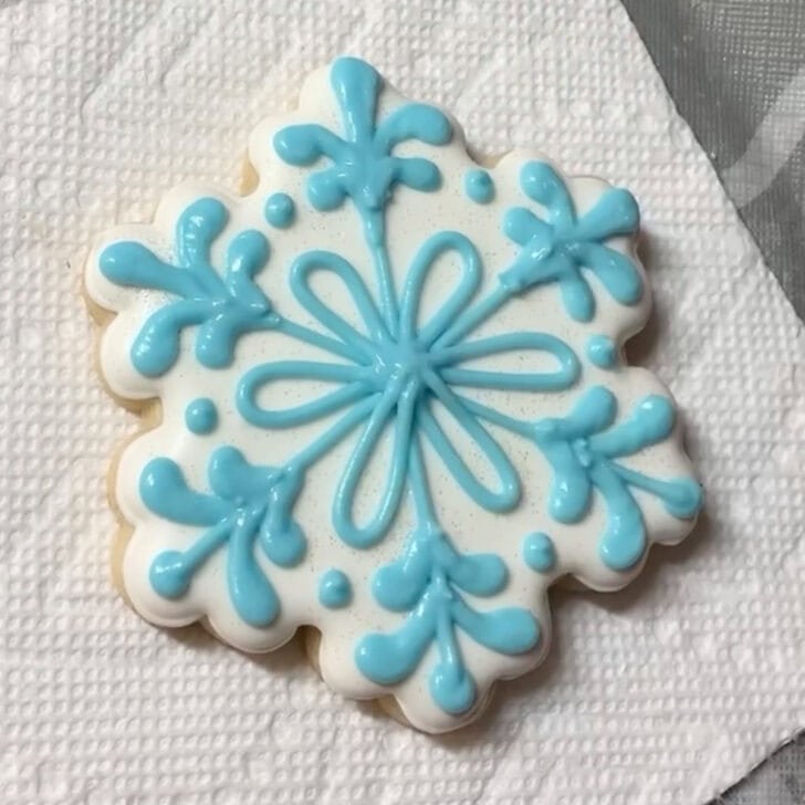 Step-by-step decorating instructions for how to decorate snowflake cookies with royal icing