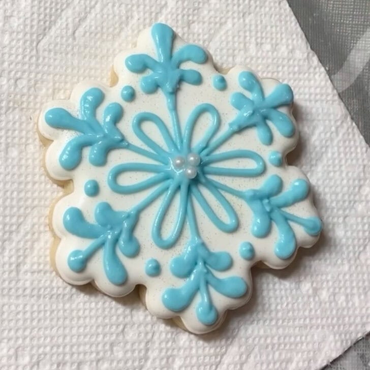 Step-by-step decorating instructions for how to decorate snowflake cookies with royal icing