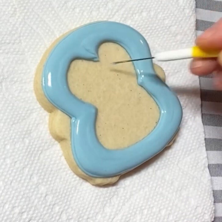Step-by-step decorating instructions for how to decorate penguin sugar cookies with realizing