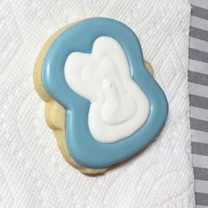 Step-by-step decorating instructions for how to decorate penguin sugar cookies with realizing