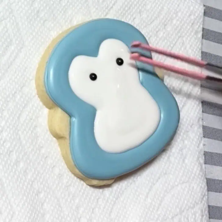 Step-by-step decorating instructions for how to decorate penguin sugar cookies with realizing