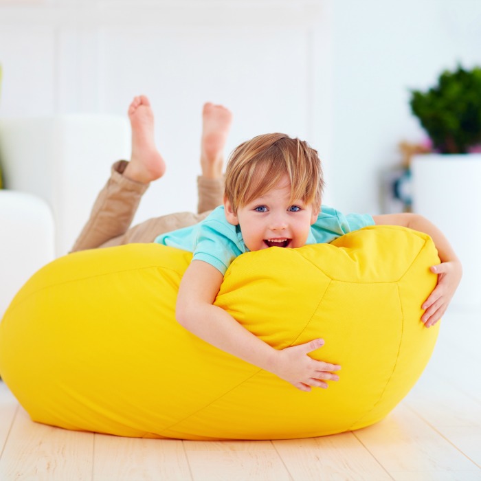 Child lying on a yellow beanbag chair for deep pressure sensory input
