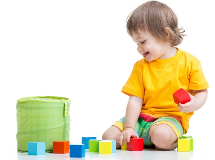 child putting colorful blocks into a container