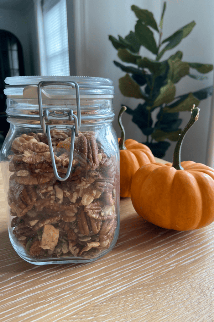 A Healthy Fall Trail Mix You'll Love. Mason jar full of trail mix next to two mini pumpkins.
