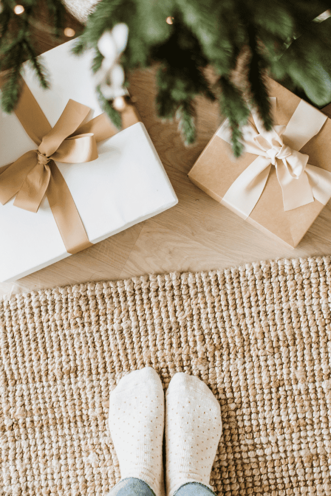 Gifts Under $25 That Anyone Would Love to Receive. Presents wrapped in brown and white paper, underneath pine branches.