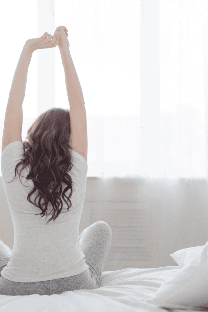 5 Morning Routines to Start Your Day Off Strong. Person waking up and stretching.