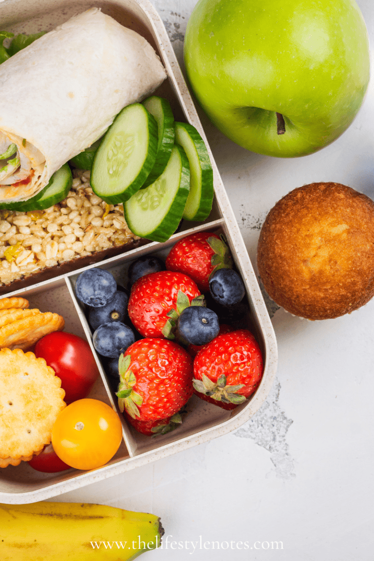 Easy lunch box ideas for kids. Bento box with berries, veggies, wrap. Muffin and apple on the side.