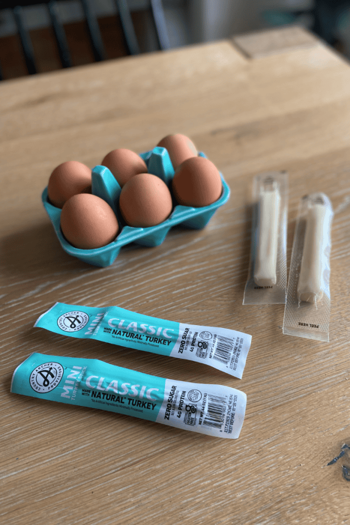 6 hard boiled eggs, 2 string cheese and 2 beef sticks on table.