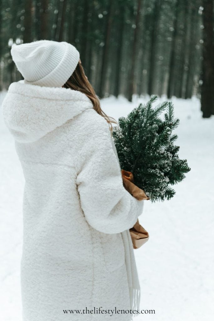 Tiny Habits to Start in the New Year. Woman outside in the winter, carrying a handful of evergreen branches.