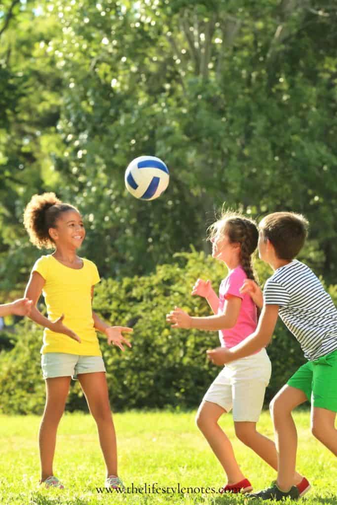 50+ Screen Free Activities for Kids. 3 kids playing with a ball outside in the summer.