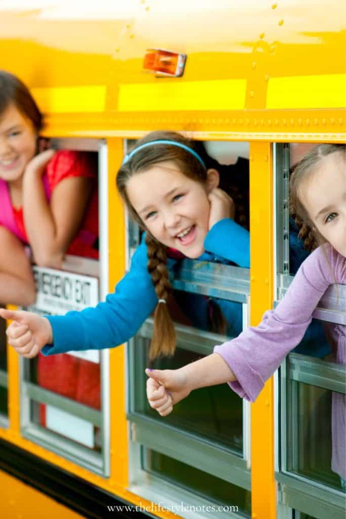 Back to School Essentials for Kids. Kids waving out of school bus windows.