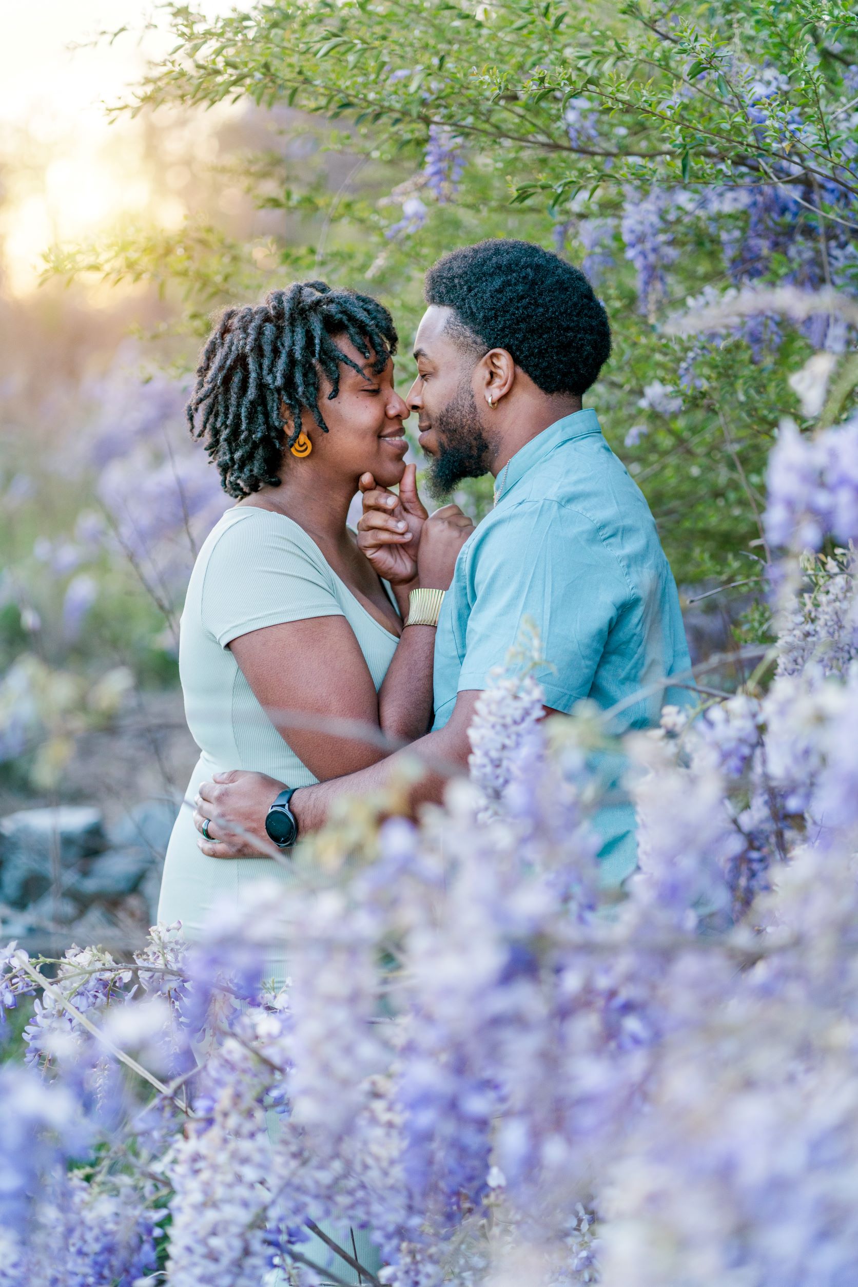 LaVianca and Shakim are nose to nose among a sea of purple wisteria flowers.
